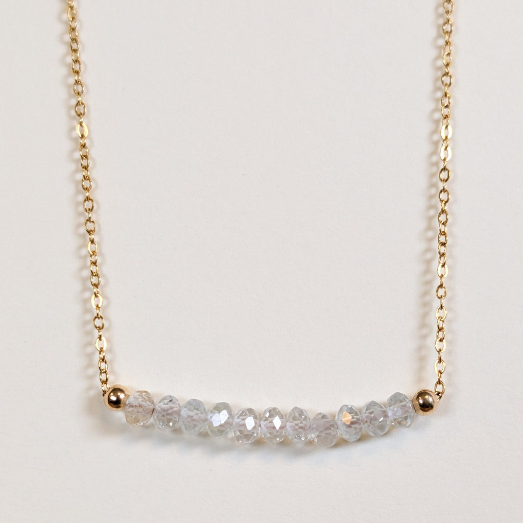 April birthstone necklace with faceted white topaz beads on a gold chain