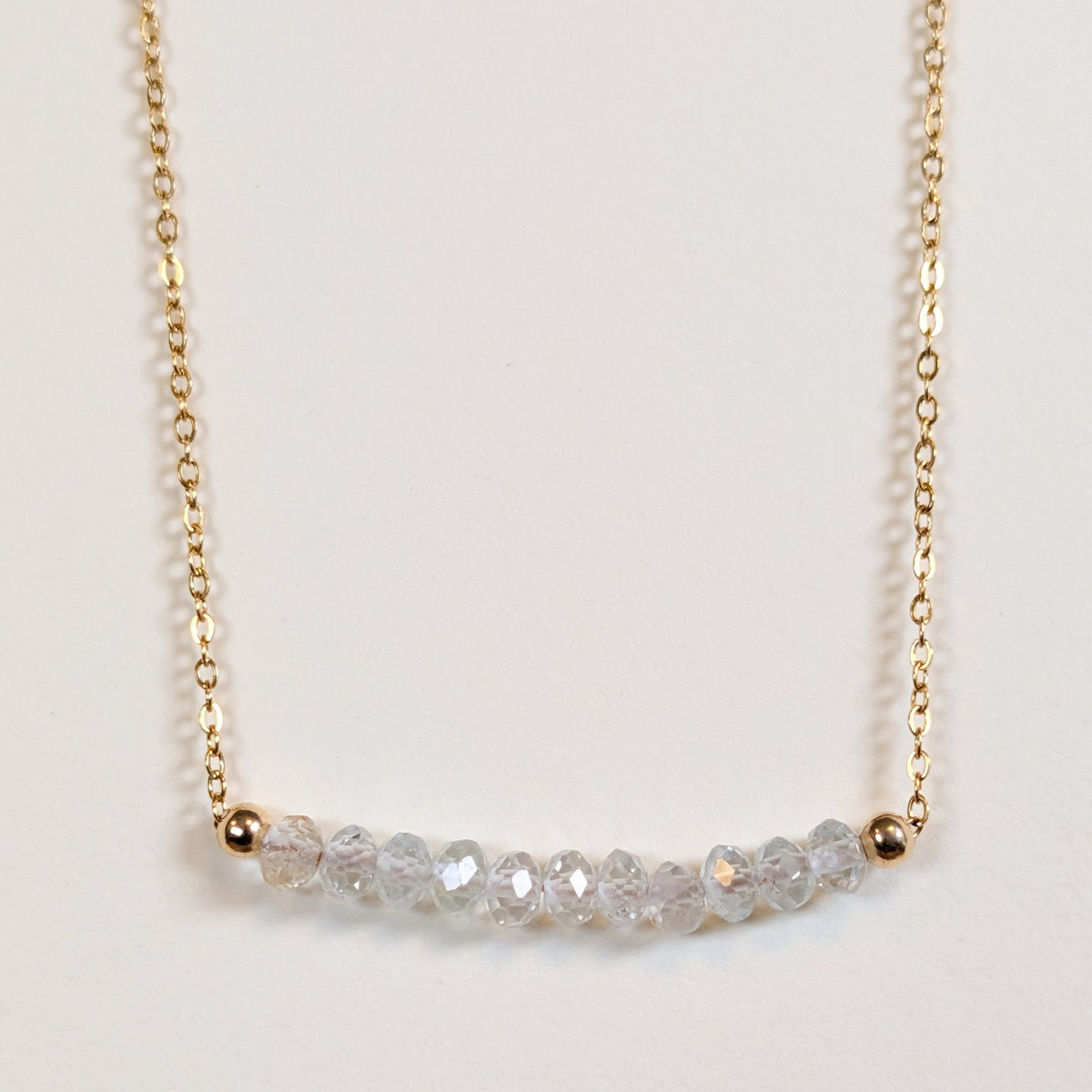 April birthstone necklace with faceted white topaz beads on a gold chain