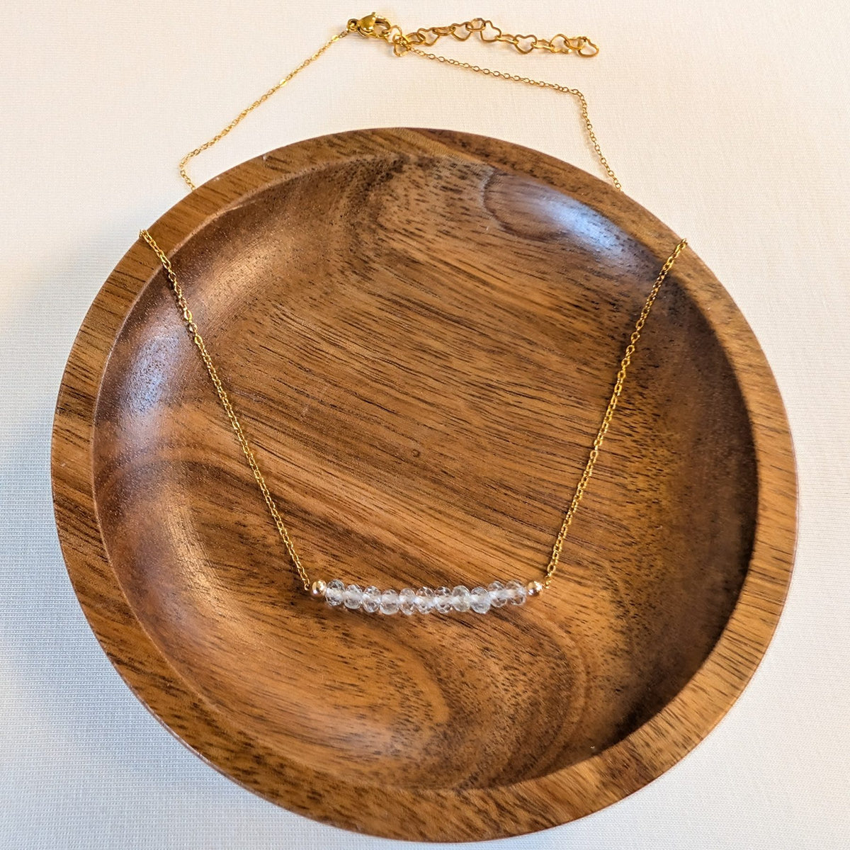 April white topaz birthstone necklace in a wooden dish