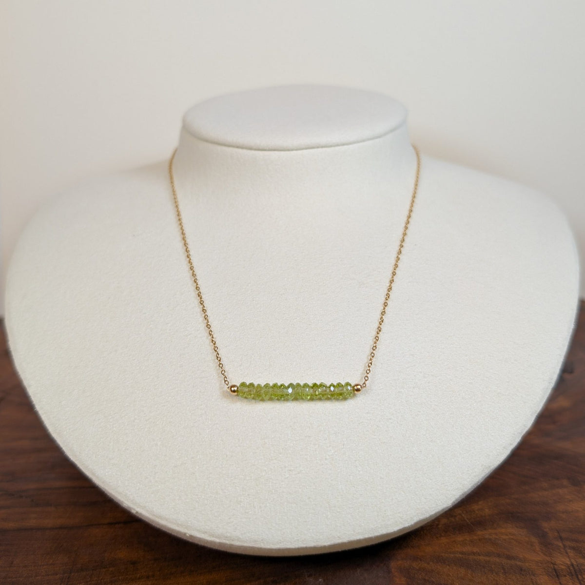 August peridot birthstone necklace on a jewelry display bust