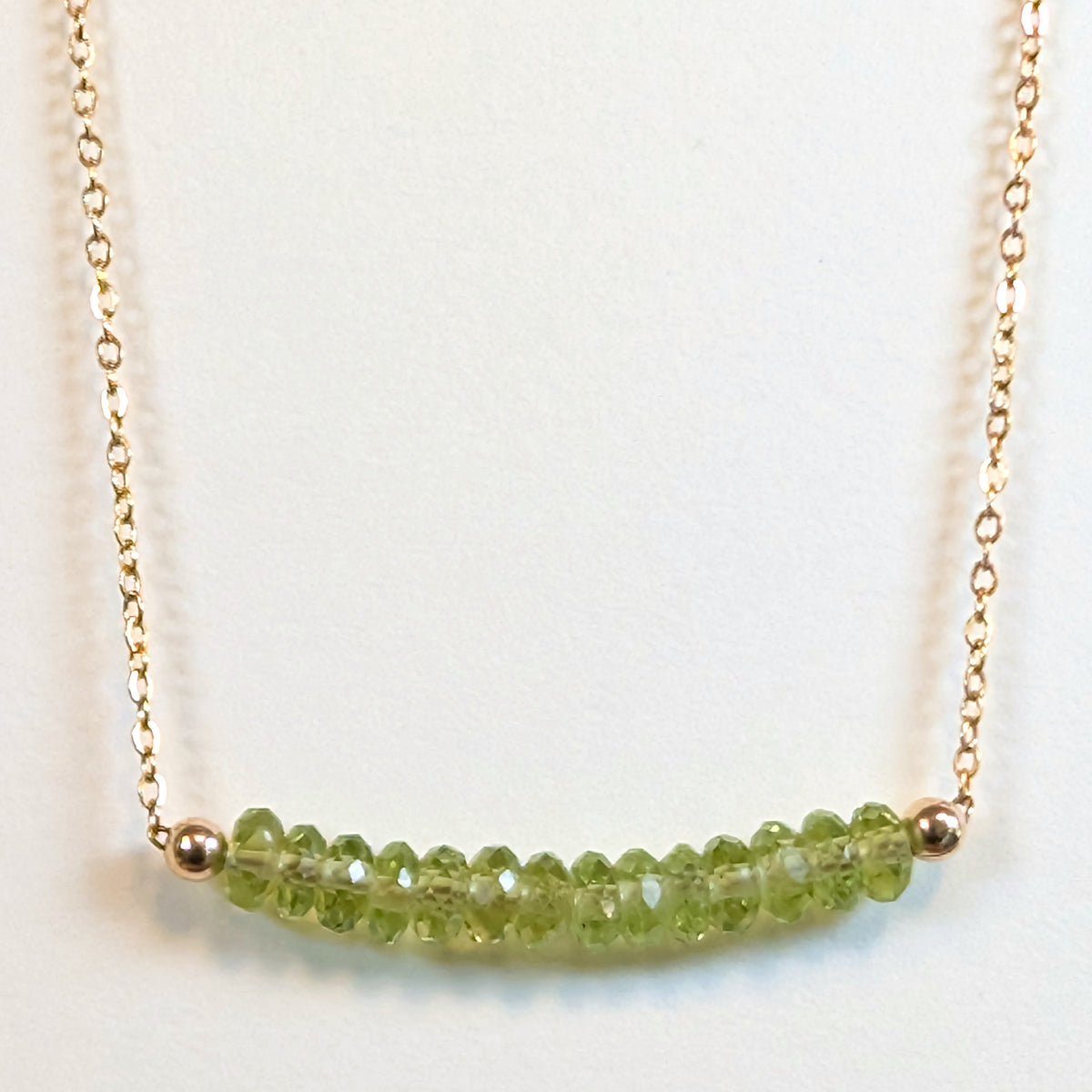August birthstone necklace with faceted peridot beads on a gold chain