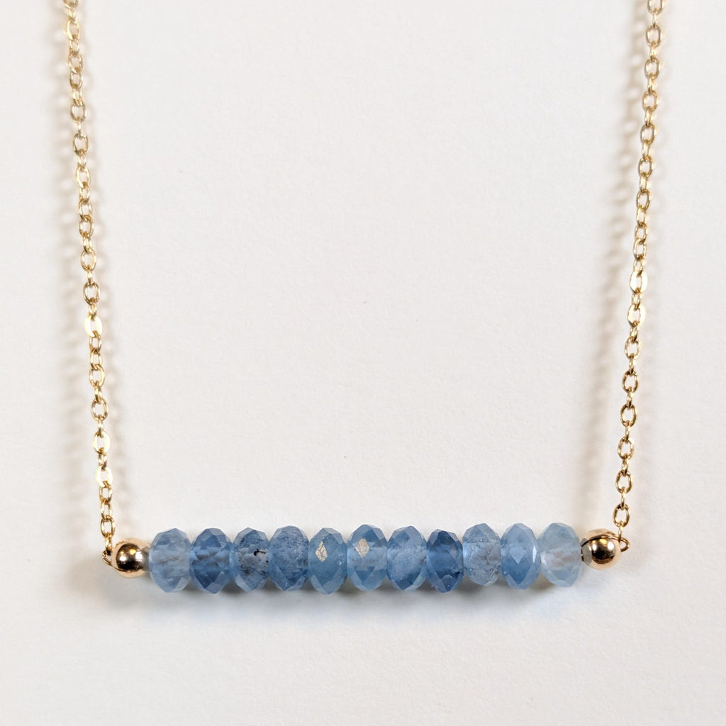 December birthstone necklace with faceted blue topaz beads on a gold chain
