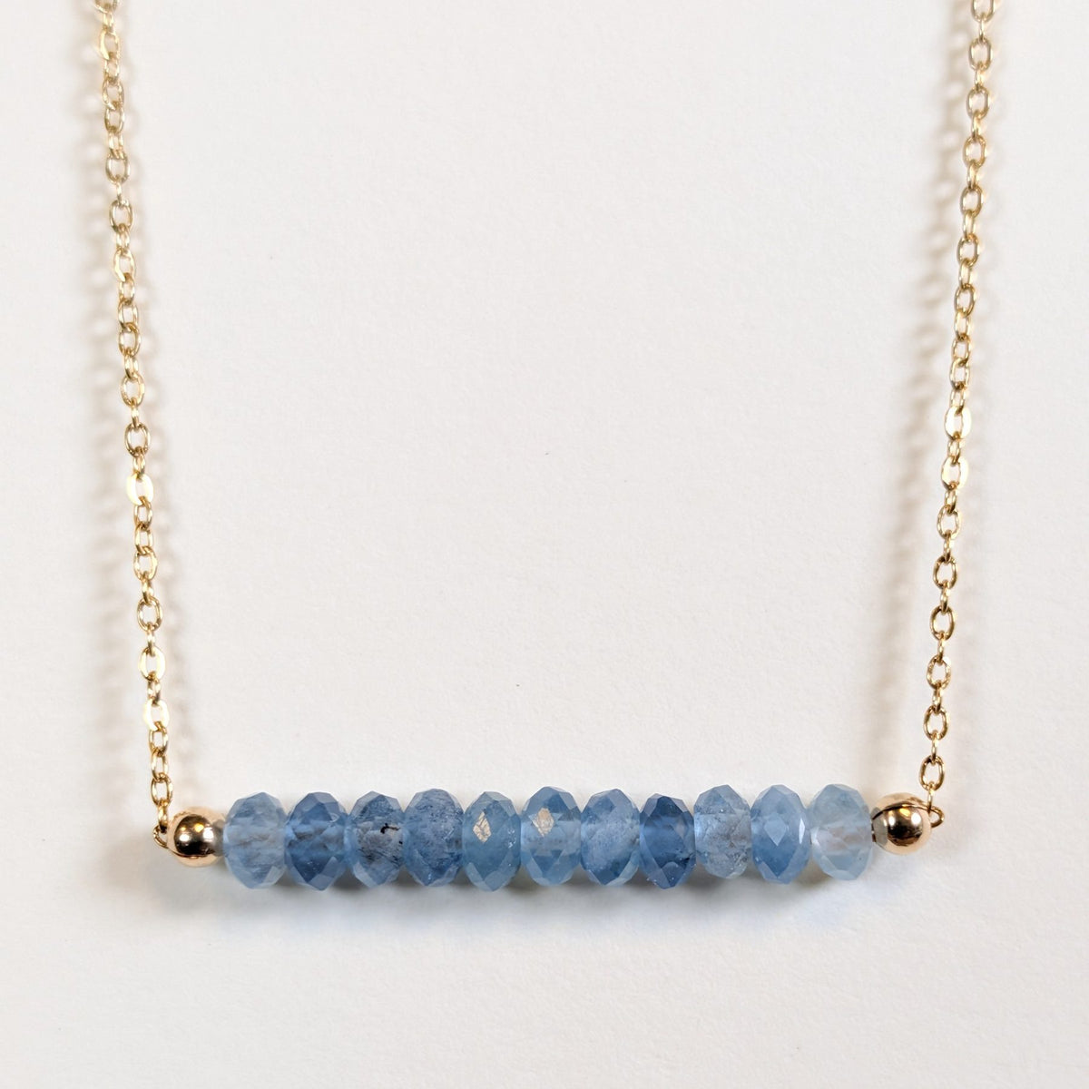 December birthstone necklace with faceted blue topaz beads on a gold chain
