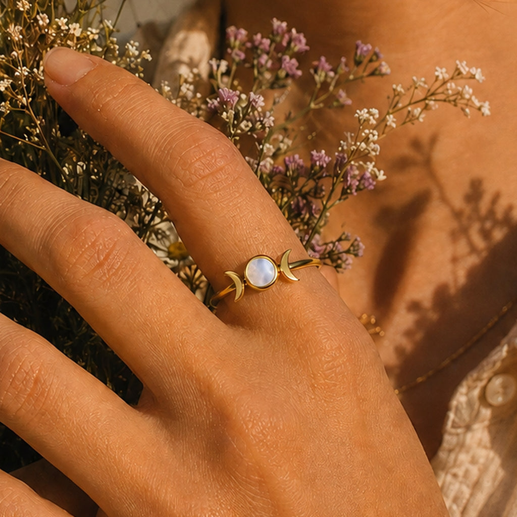 Moon Goddess Ring in rainbow moonstone worn on the hand with dried flowers behind