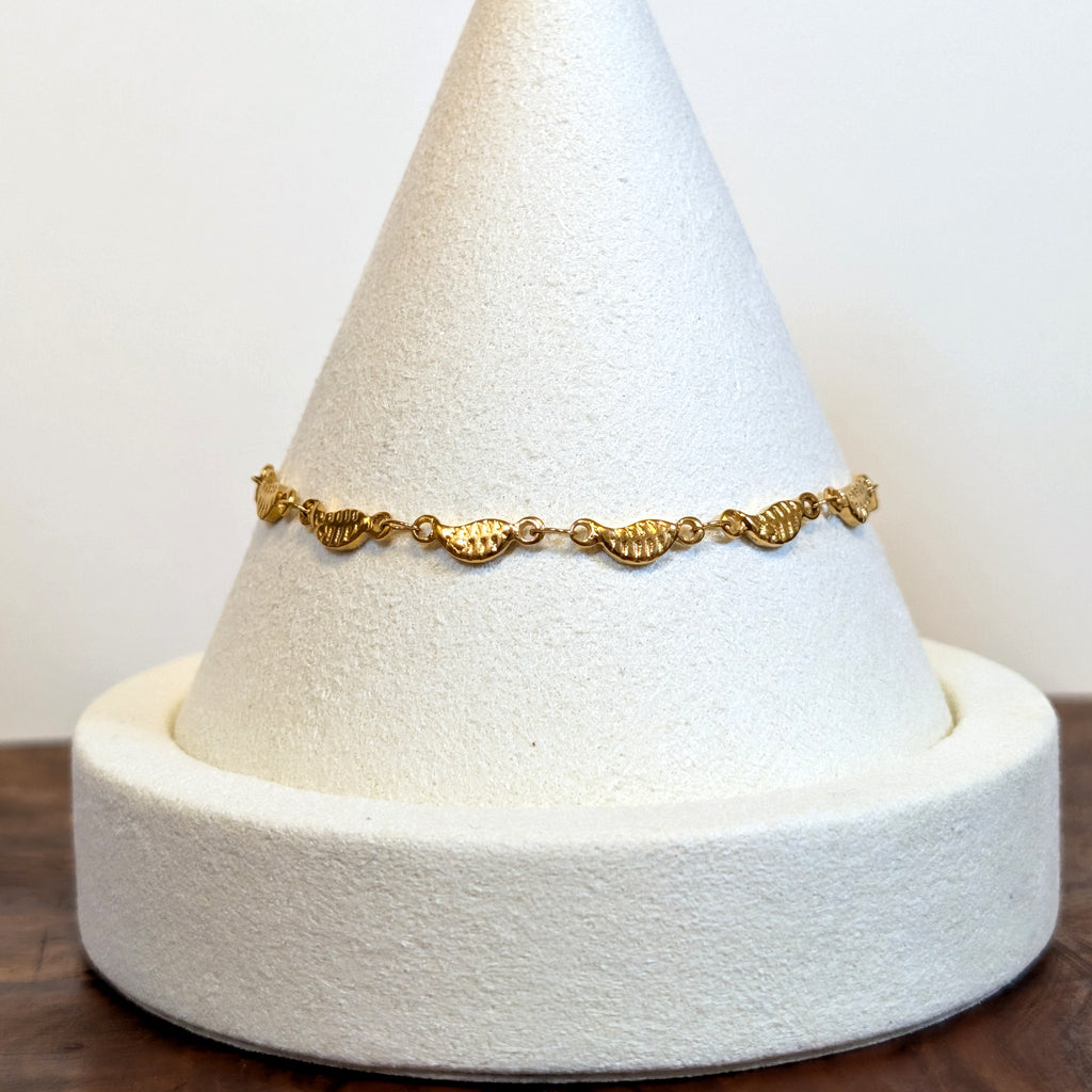 Falling Leaves gold bracelet with a trail of tiny leaf links, shown on a display cone