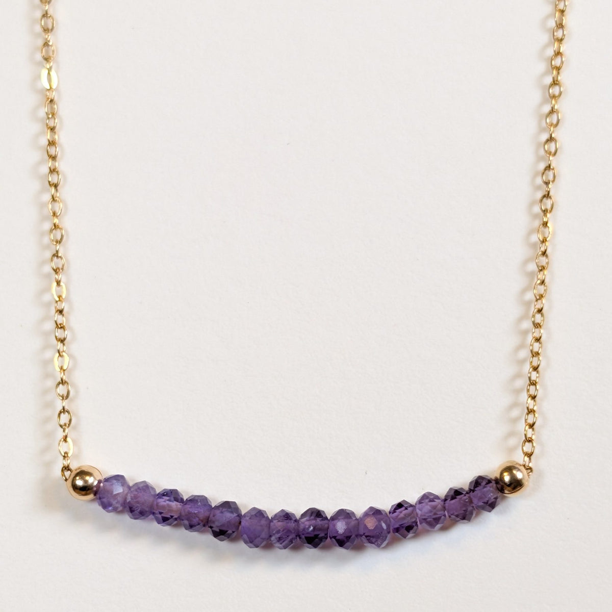 February birthstone necklace with faceted amethyst beads on a gold chain