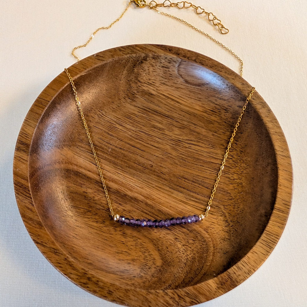 February amethyst birthstone necklace in a wooden dish