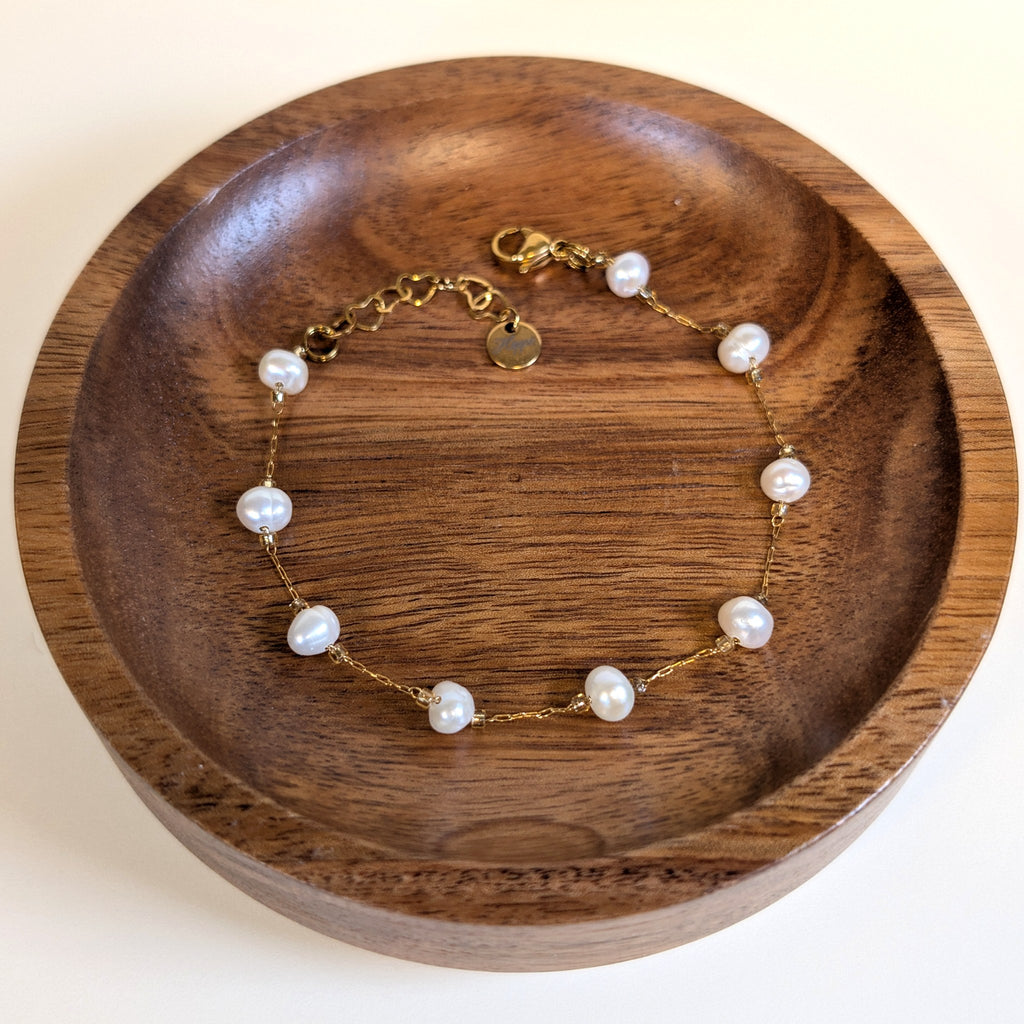 Floating Pearls freshwater pearl bracelet with lobster clasp and heart-link extender, shown in a walnut dish