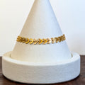 Golden Vine gold bracelet with a continuous laurel-leaf chain, shown on a display cone