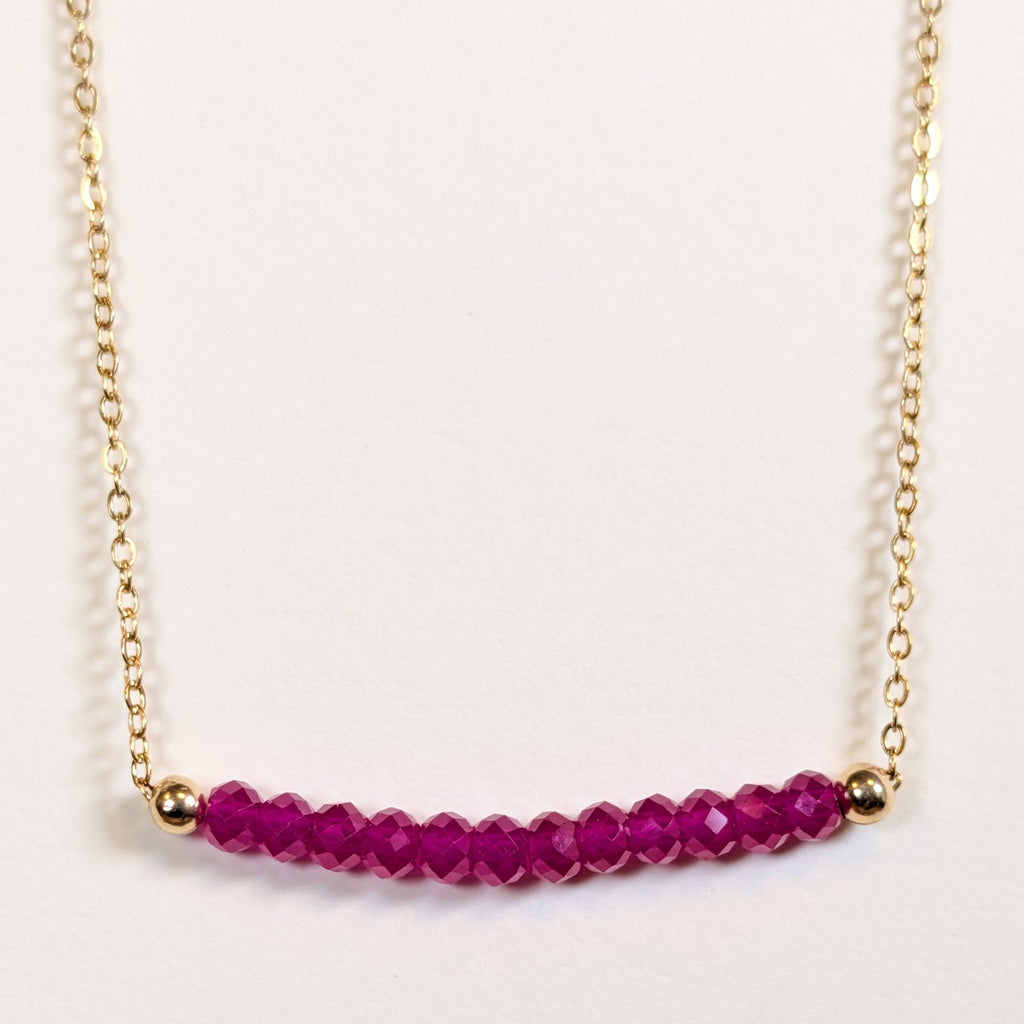 July birthstone necklace with faceted ruby beads on a gold chain