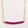 July birthstone necklace with faceted ruby beads on a gold chain