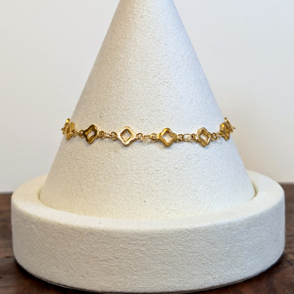 Lucky Clover gold bracelet with four-leaf clover links, shown on a display cone