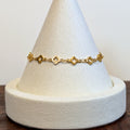 Lucky Clover gold bracelet with four-leaf clover links, shown on a display cone