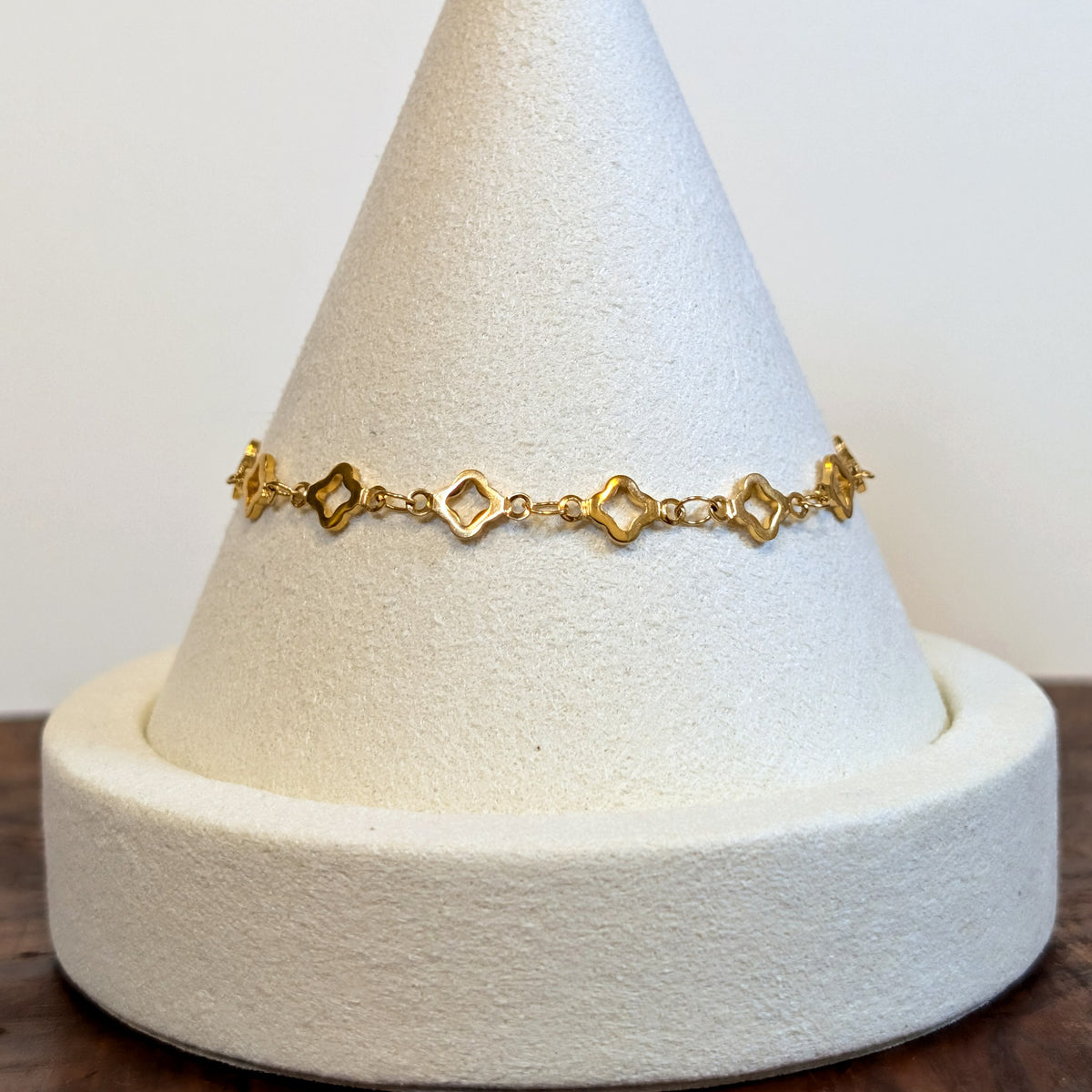 Lucky Clover gold bracelet with four-leaf clover links, shown on a display cone