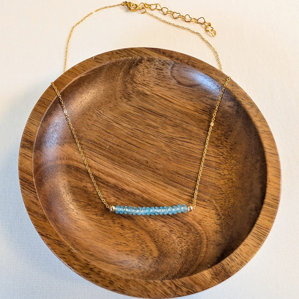 March aquamarine birthstone necklace in a wooden dish
