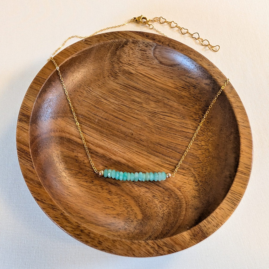 May emerald birthstone necklace in a wooden dish