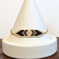 Handwoven Miyuki Delica bar bracelet in black, bronze and gold on a delicate gold chain