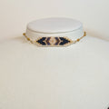 Miyuki beaded choker with cream and gold chevrons around a navy core, on a white display bust