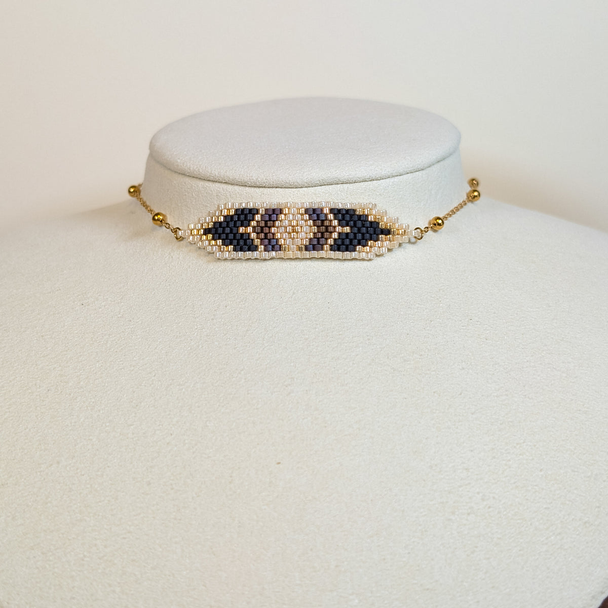 Miyuki beaded choker with cream and gold chevrons around a navy core, on a white display bust