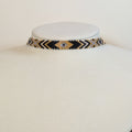 Wide Miyuki beaded choker band in black, gold, silver and grey arrow patterns, on a white display bust