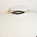 Miyuki beaded choker in black and gold with a pale eye at the centre, on a white display bust