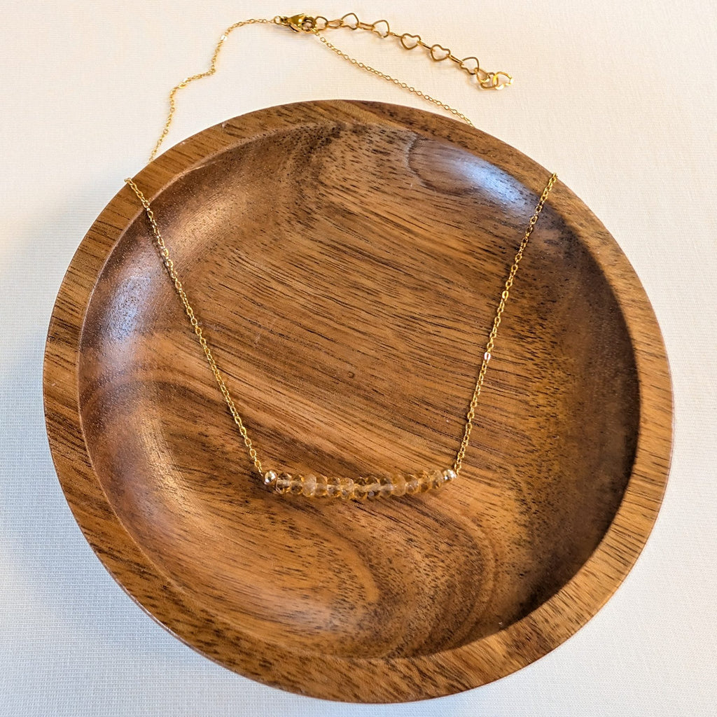 November citrine birthstone necklace in a wooden dish
