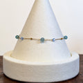 Ocean Mist bracelet with natural agate beads and crystal cubes on a fine gold chain, shown on a display cone