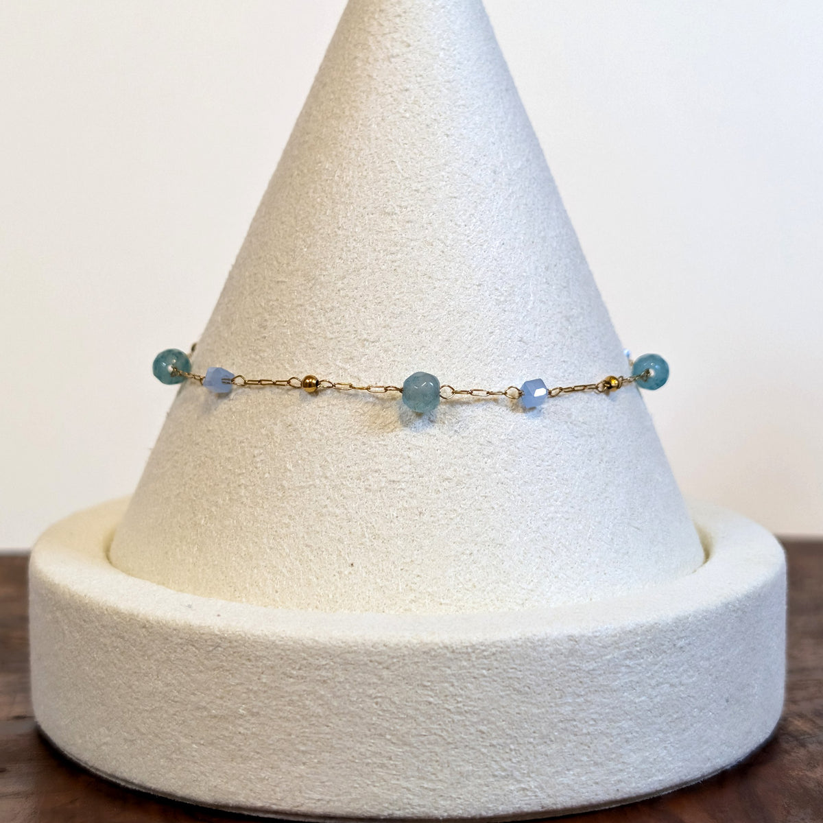 Ocean Mist bracelet with natural agate beads and crystal cubes on a fine gold chain, shown on a display cone