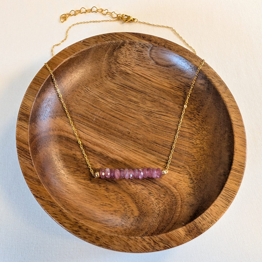 October tourmaline birthstone necklace in a wooden dish