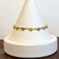 Puffy Heart gold bracelet with solid rounded heart links, shown on a display cone