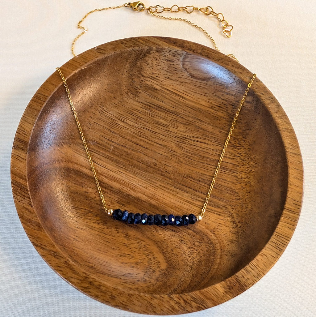 September sapphire birthstone necklace in a wooden dish