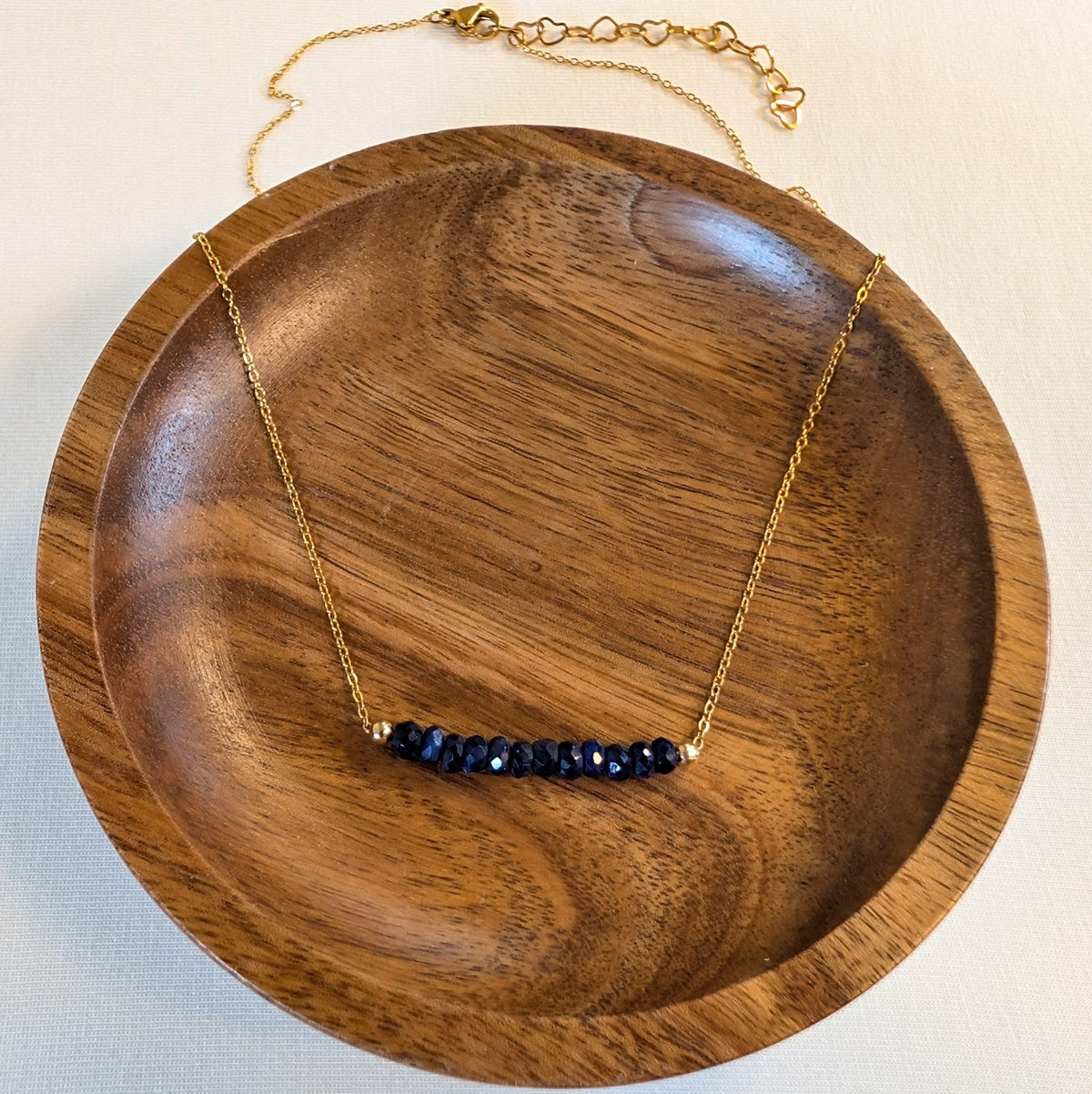 September sapphire birthstone necklace in a wooden dish