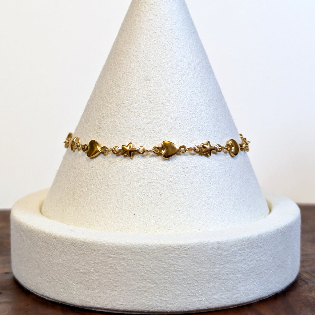 Starry Heart gold bracelet with alternating solid hearts and stars, shown on a display cone