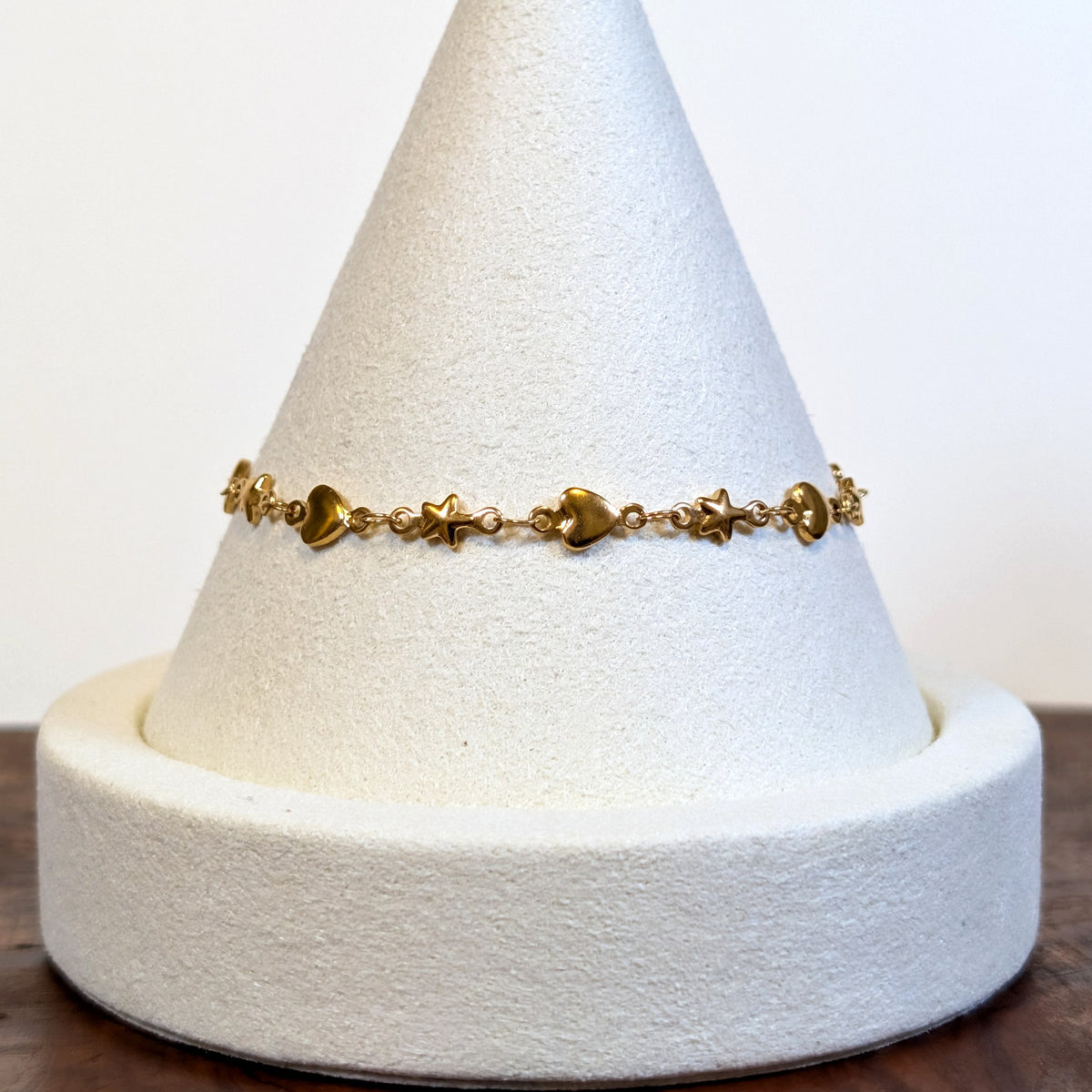 Starry Heart gold bracelet with alternating solid hearts and stars, shown on a display cone
