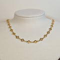 Gold-tone stainless steel choker chain of open four-petal clover links on a white display bust