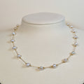 Gold-tone stainless steel fine chain choker with pearls spaced along it on a white display bust