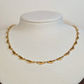 Gold-tone stainless steel choker chain of ribbed scallop shell links on a white display bust