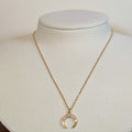 Gold-tone stainless steel necklace with a stone-set crescent horn pendant on a white display bust