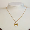Gold-tone stainless steel necklace with a cut-out mountain range in a circle pendant on a white display bust