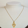 Gold-tone stainless steel necklace with a cut-out mountain range in a diamond frame on a white display bust