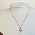 Gold-tone stainless steel necklace with an elongated four-point north star pendant on a white display bust