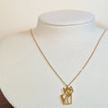 Gold-tone stainless steel necklace with a cut-out origami cat pendant on a white display bust