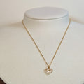 Gold-tone stainless steel necklace with a pave-set open heart pendant on a white display bust