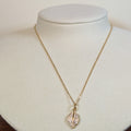 Gold-tone stainless steel necklace with a pave-set leaf pendant on a white display bust
