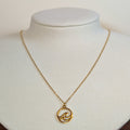 Gold-tone stainless steel necklace with a cut-out wave in a circle pendant on a white display bust